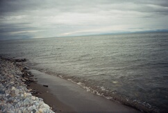 участок пляжа, крупный чёрный песок,Байкал в августе.